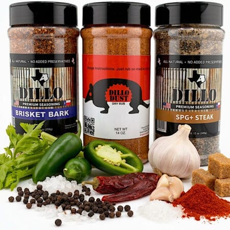 Three clear plastic spice shakers filled with BBQ seasoning rubs stand side by side against a solid black background. On the left is Brisket Bark Premium Seasoning (9 oz / 255g) with a dark blue label. In the center is Dillo Dust Dry Rub (14 oz) featuring a red and white label with an armadillo silhouette. On the right is SPG+ Steak Premium Seasoning (12 oz / 340g) with a tan label.